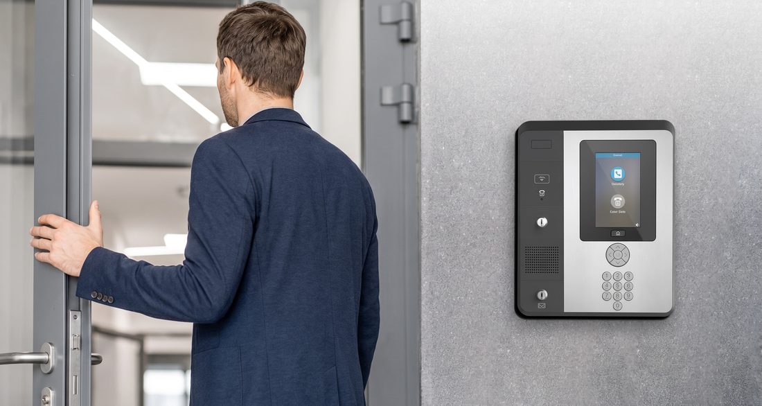 A man opening a door beside a keypad entry station
