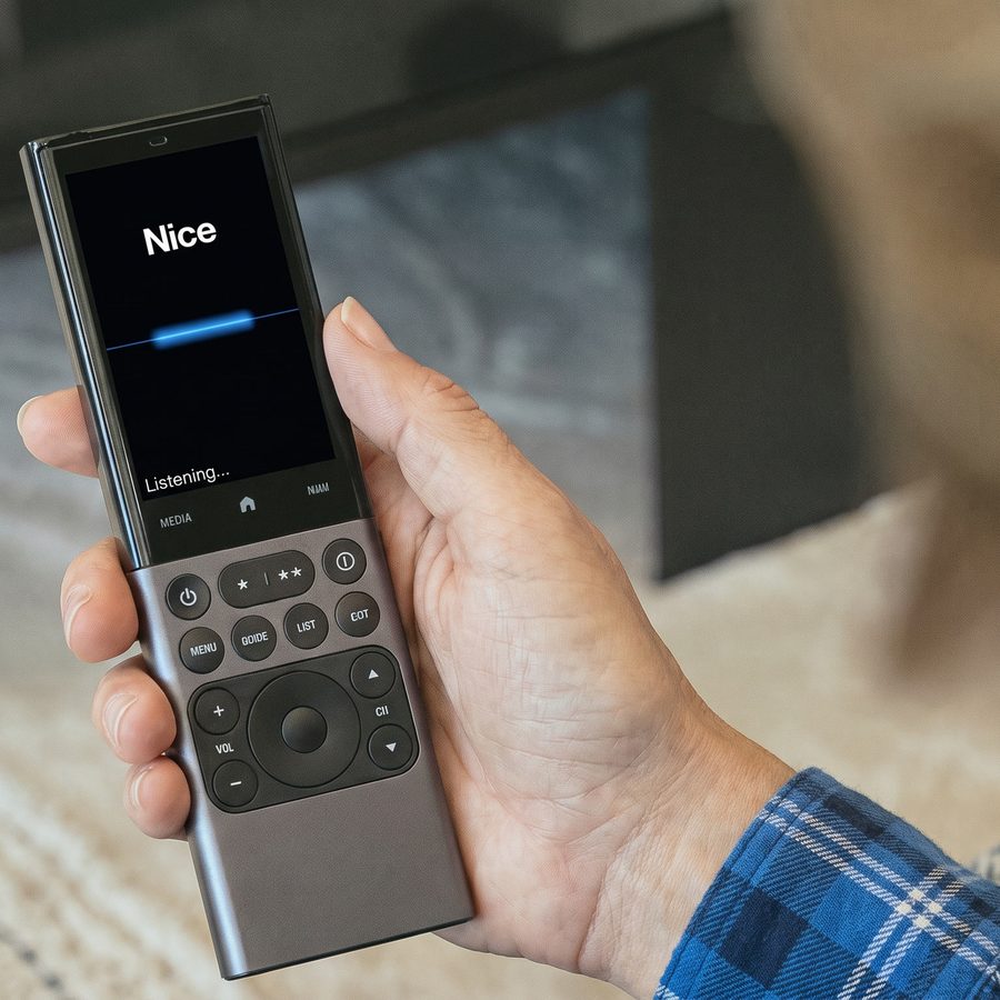 A hand holding a voice remote in a living room
