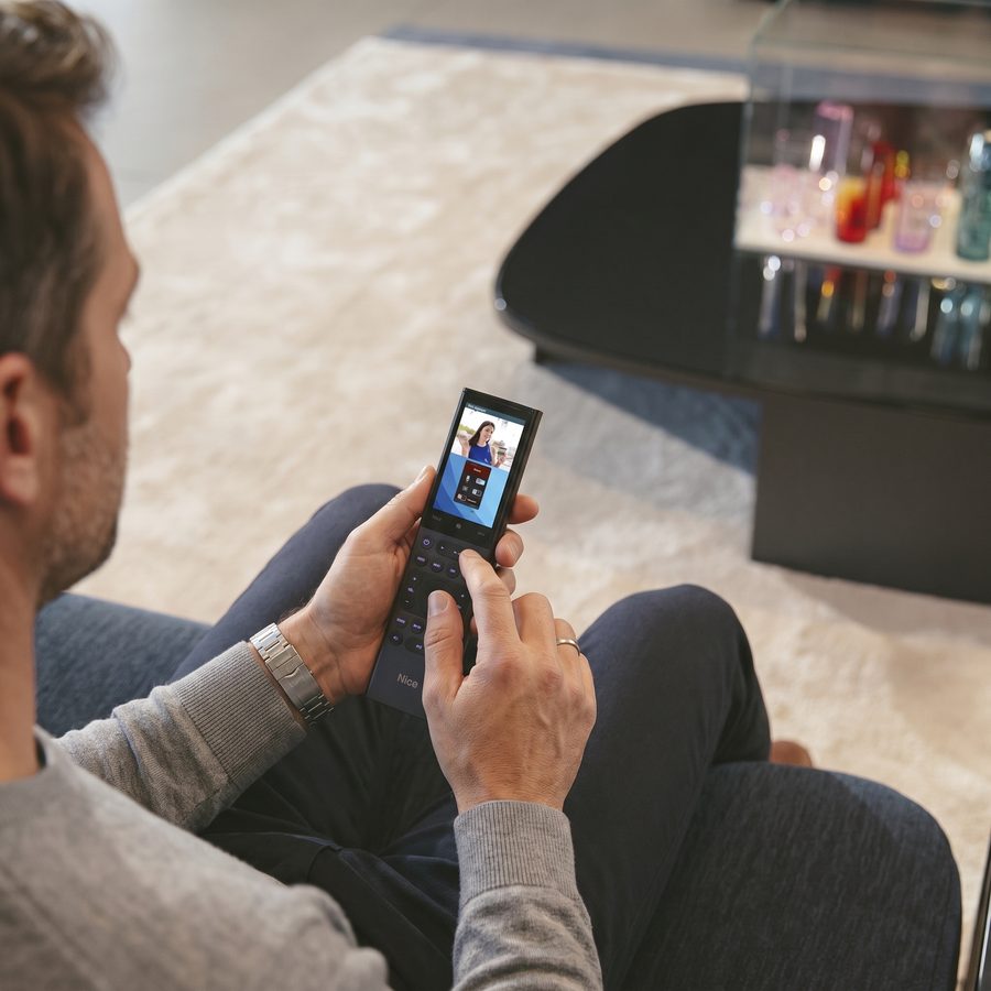 A man on a sofa watching a video doorbell feed on a phone