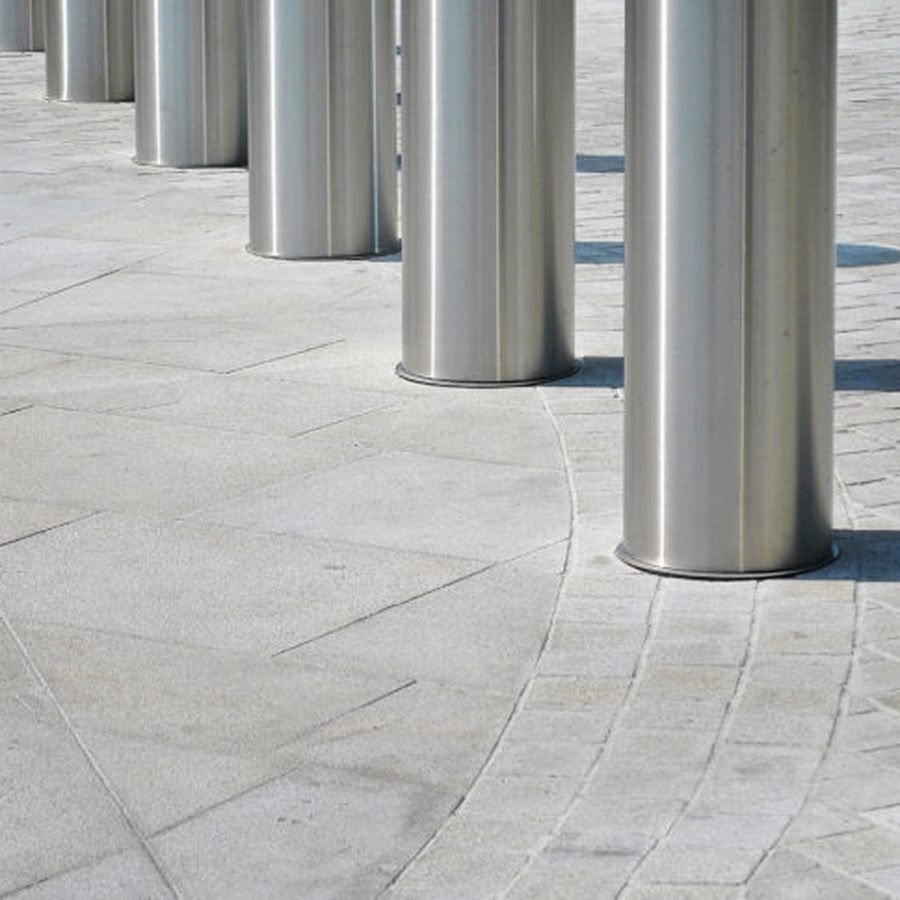 A row of steel crash-rated bollards in front of a building
