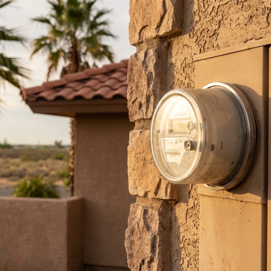 An electric meter on a stucco wall