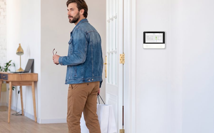 A man walking in the front door past the security panel